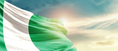 Nigeria waving flag in beautiful sky with sun
