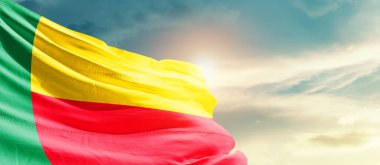 Benin waving flag in beautiful sky with sun