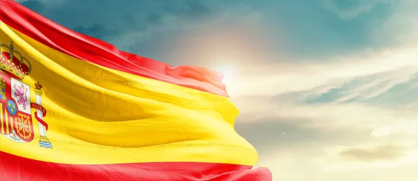Spain waving flag in beautiful sky with sun