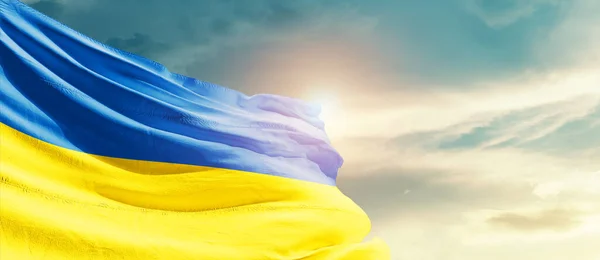 Ukraine waving flag in beautiful sky with sun