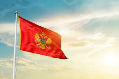 Montenegro waving flag in beautiful sky with sun