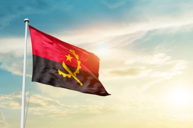 Angola waving flag in beautiful sky with sun