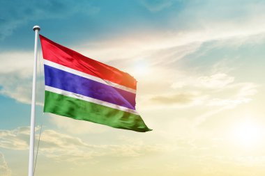 Gambia waving flag in beautiful sky with sun