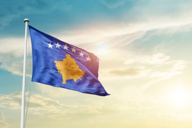 Kosovo waving flag in beautiful sky with sun