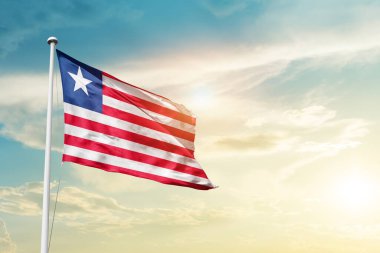 Liberia waving flag in beautiful sky with sun