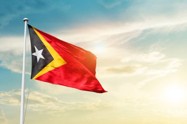 East Timor waving flag in beautiful sky with sun