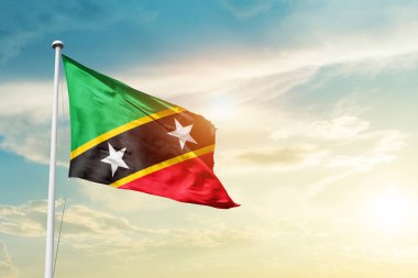 Saint Kitts and Nevis waving flag in beautiful sky with sun
