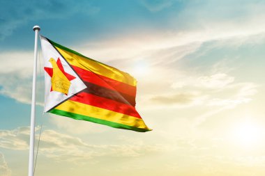 Zimbabwe waving flag in beautiful sky with sun