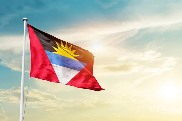 stock image Antigua and Barbuda waving flag in beautiful sky with sun