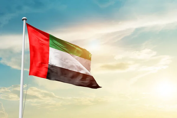 United Arab Emirates waving flag in beautiful sky with sun