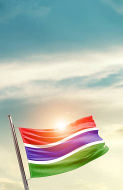 Gambia waving flag in beautiful sky with sun
