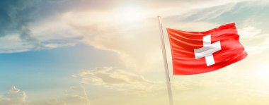 Switzerland waving flag in beautiful sky with sun