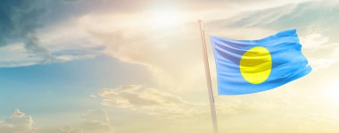 Palau waving flag in beautiful sky with sun