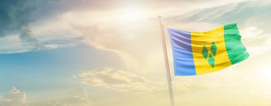 Saint Vincent and the Grenadines waving flag in beautiful sky with sun