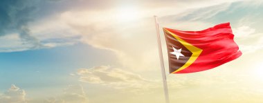 East Timor waving flag in beautiful sky with sun