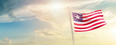 Liberia waving flag in beautiful sky with sun