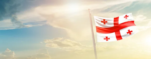 stock image Georgia waving flag in beautiful sky with sun