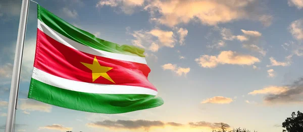 stock image Suriname waving flag in beautiful sky with clouds