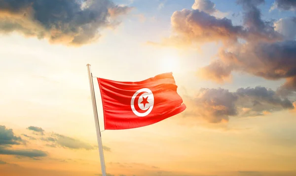 stock image Tunisia waving flag in beautiful sky with clouds and sun