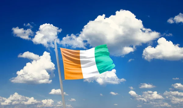 stock image Ivory island waving flag in beautiful sky with clouds