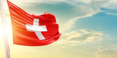 İsviçre bayrağı bulutlu ve güneşli gökyüzüne karşı