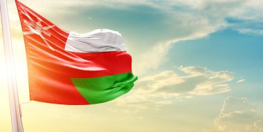 Umman bayrağı gökyüzüne karşı bulutlar ve güneşle