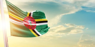 Dominika bayrağı bulutlu ve güneşli gökyüzüne karşı