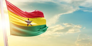 Gana bayrağı bulutlu ve güneşli gökyüzüne karşı