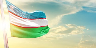 Özbekistan bayrağı bulutlu ve güneşli gökyüzüne karşı