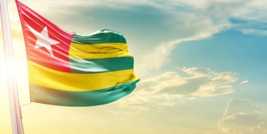 Togo bayrağı bulutlu ve güneşli gökyüzüne karşı