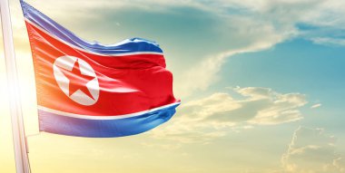 Kuzey Kore bayrağı bulutlu ve güneşli gökyüzüne karşı