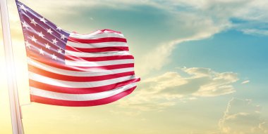 Birleşik Devletler bayrağı bulutlu ve güneşli gökyüzüne karşı