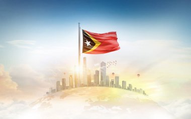 Şehir manzarasına karşı Doğu Timor bayrağı dalgalanıyor