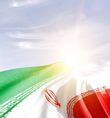 İran bayrağı güneşle gökyüzüne doğru dalgalanıyor