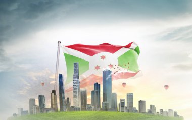 Burundi ulusal bayrağı gökyüzüne ve şehir binalarına doğru dalgalanıyor. 