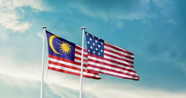 Malezya ve ABD bayrakları bulutlu mavi gökyüzüne karşı rüzgarda dalgalanıyor