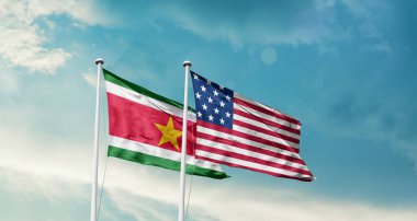 Surinam ve ABD bayrakları rüzgarda dalgalanıyor bulutlu mavi gökyüzüne karşı