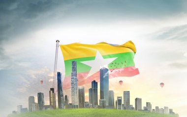 Myanmar Ulusal Bayrağı gökyüzüne ve şehir mimarisine karşı dalgalanıyor 