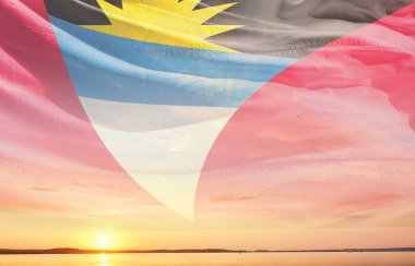 Antigua ve Barbuda ulusal bayrağı gün batımında gökyüzüne doğru dalgalanıyor 