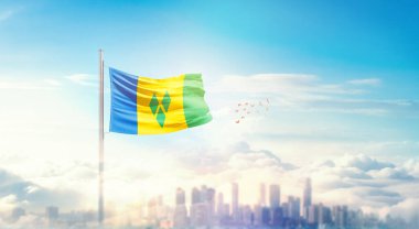 Saint Vincent ve Grenadines Ulusal Bayrağı güzel bir bina siluetinde sallanıyor 