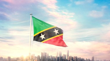 Saint Kitts ve Nevis bayrağı mavi gökyüzü arka planında dalgalanan şehir manzarası 