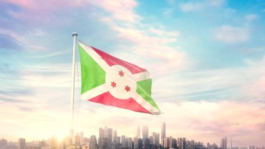 Burundi bayrağı mavi gökyüzü arka planında şehir manzarası ile dalgalanıyor 