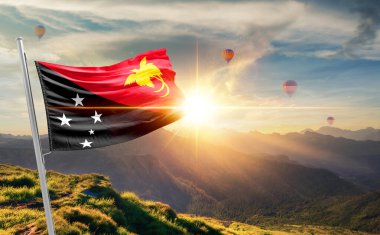 Papua Yeni Gine günbatımında bayrak sallıyor. Arka planda sıcak hava balonları ile dağlarda.