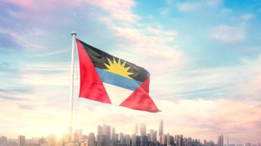 Antigua ve Barbuda bayrağı mavi gökyüzü arka planında şehir manzarası ile dalgalanıyor 