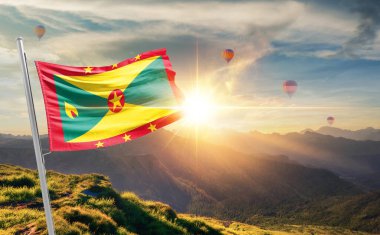 Gün batımında Grenada bayrağını sallıyor ve arka planda sıcak hava balonları var.