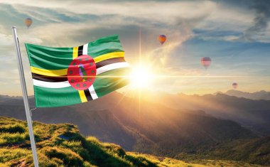 Dominica bayrağı dağlarda gün batımında sallanıyor, arka planda sıcak hava balonları 