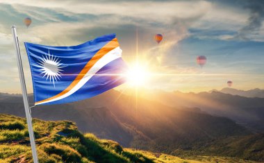 Marshall Adaları bayrağı dağlarda gün batımında dalgalanıyor, arka planda sıcak hava balonları 