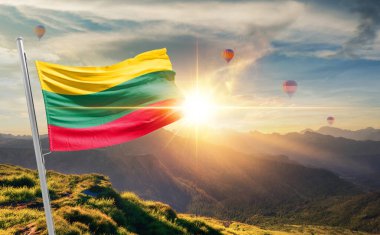 Litvanya günbatımında arka planda sıcak hava balonlarıyla bayrak sallıyor 