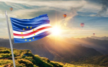 Cabo Verde arka planda sıcak hava balonları ile günbatımında bayrak sallıyor 