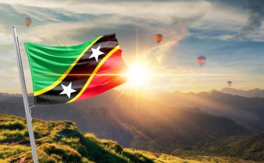 Saint Kitts ve Nevis arka planda sıcak hava balonlarıyla gün batımında bayrak sallıyor. 